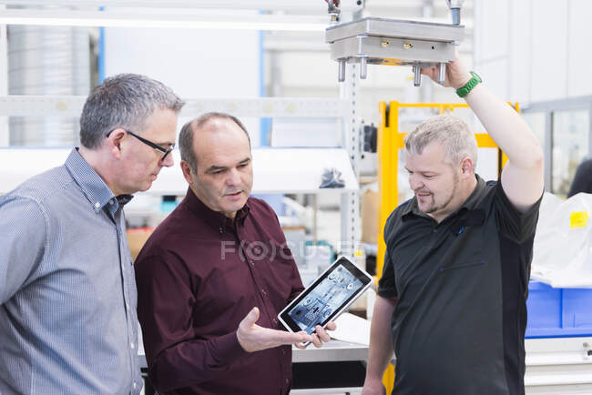 Drei Männer mit Tablet diskutieren in Fabrik — Stockfoto