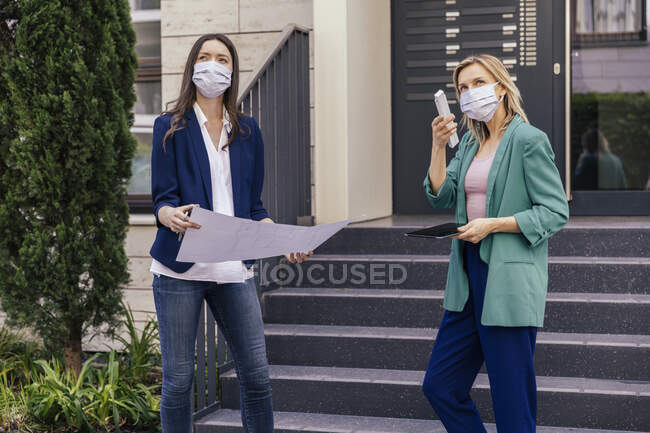Two real estate agents wearing face masks while inspection outdoor area of house — Stock Photo