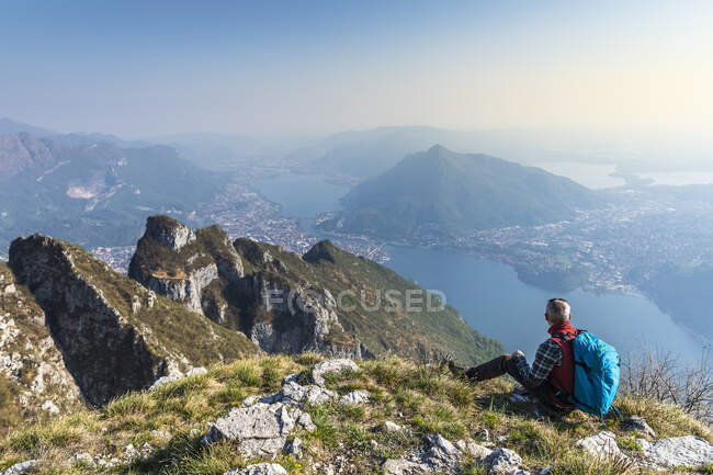 Vista trasera del excursionista sentado en la cima de la montaña, Alpes Orobie, Lecco, Italia - foto de stock