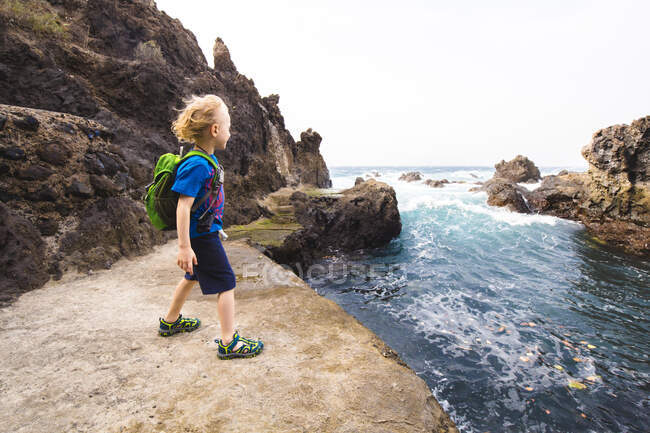 Вивчаючи море в Коста - Адеже (Канарські острови, Іспанія), хлопчик стоїть на скелі. — стокове фото