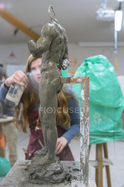 Étudiante pulvérisation d'eau sur sculpture — Photo de stock