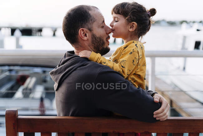Отец обнимает, пока дочь целует его в нос в городе — стоковое фото