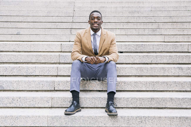 Retrato de confiante jovem empresário sentado nas escadas — Fotografia de Stock