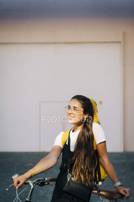 Donna premurosa con i capelli lunghi in piedi in bicicletta sulla strada in città — Foto stock