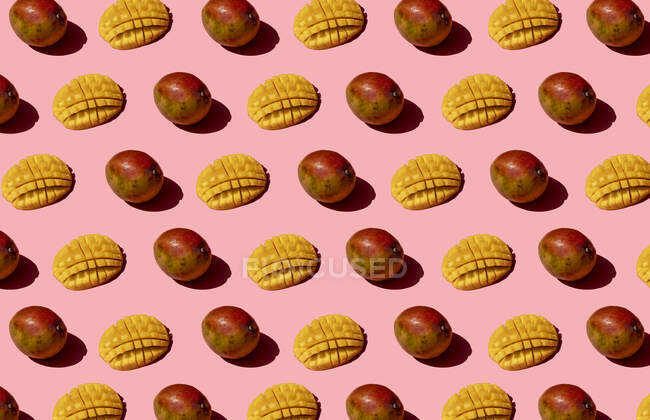 Patrón de mango entero y picado sobre fondo rosa - foto de stock