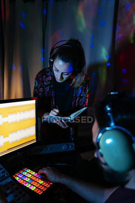 Musikerehepaar nutzt Computer im beleuchteten Tonstudio zu Hause — Stockfoto