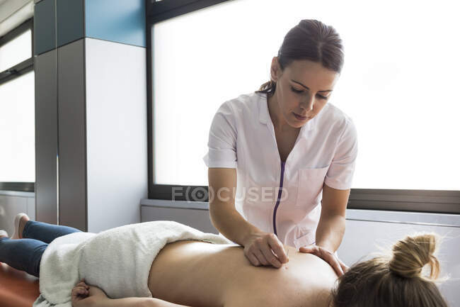 Chiudi l'agopuntore applicando aghi per agopuntura alla schiena della donna — Foto stock