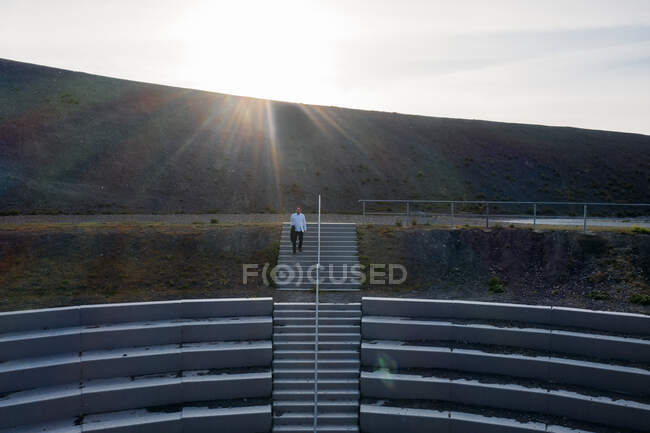 Uomo d'affari che scende dalle scale di BergArena contro il cielo durante il tramonto — Foto stock