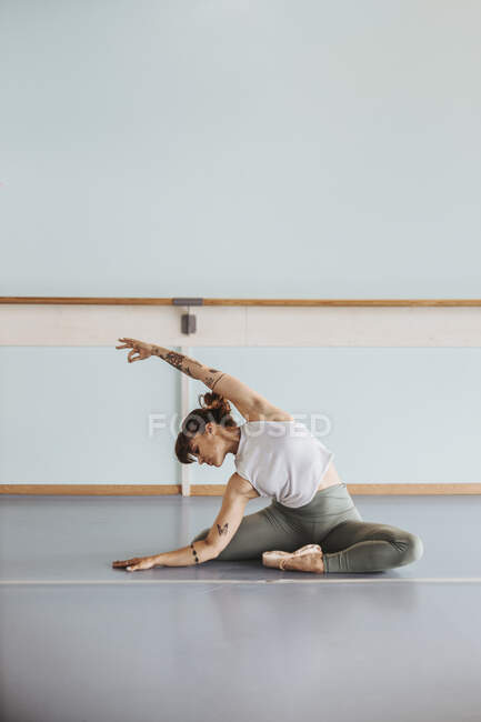 Ballerina che fa esercizi di stretching sul pavimento in studio — Foto stock