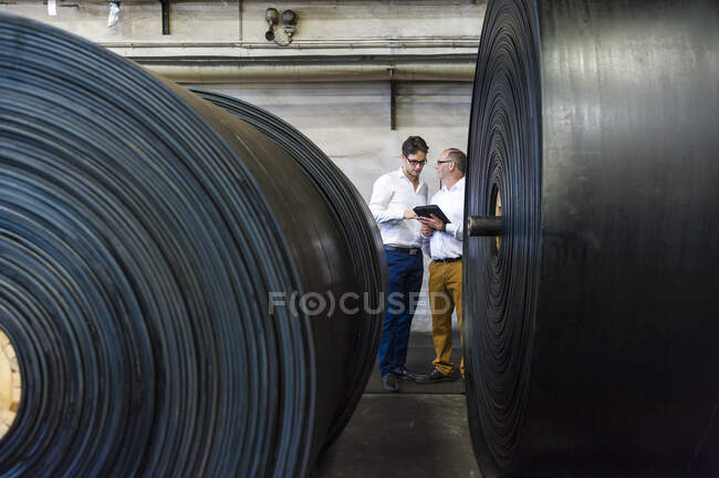 Two businessmen having a meeting in a rubber processing factory — Stock Photo