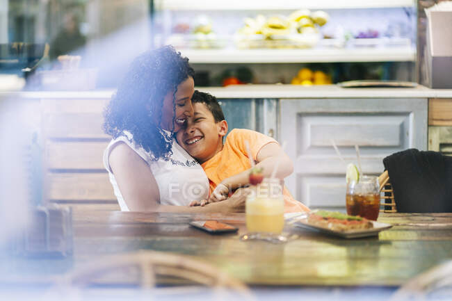 Giovane donna godendo mentre abbraccia il figlio al ristorante — Foto stock