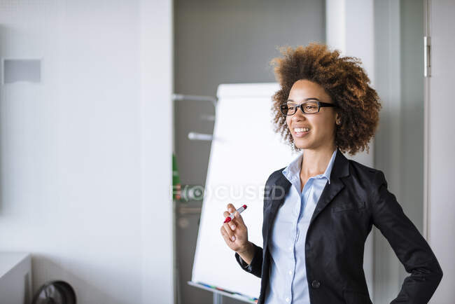 Mujer de negocios sonriente liderando una presentación en el rotafolio en la oficina - foto de stock