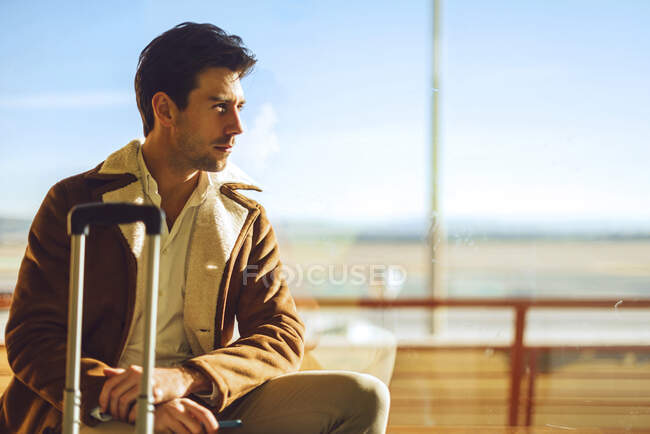 Empresário atencioso sentado no peitoril da janela na área de partida do aeroporto — Fotografia de Stock
