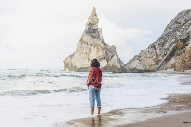 Молода жінка стоїть на березі в Прая - да - Урса (Лісабон, Португалія). — стокове фото