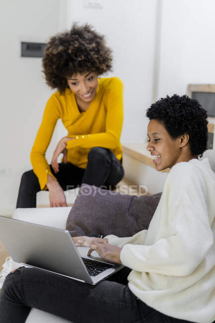 Deux amis utilisant un ordinateur portable à la maison — Photo de stock