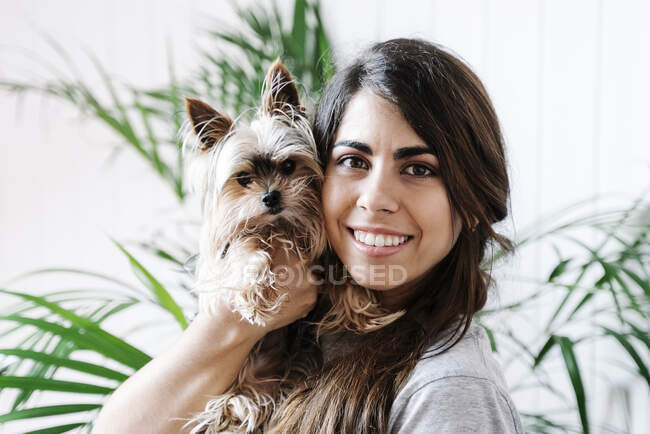 Jovem feliz carregando Yorkshire Terrier em casa — Fotografia de Stock