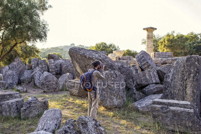 Grécia, Olímpia, Turista masculino fotografando ruínas do antigo Templo de Zeus ao pôr-do-sol — Fotografia de Stock