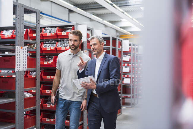 Two men talking in storehouse of a factory — Stock Photo