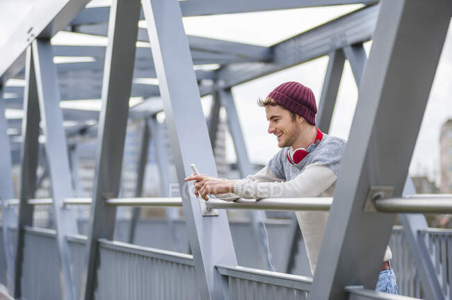 Elegante giovane uomo utilizzando smartphone su un ponte — Foto stock