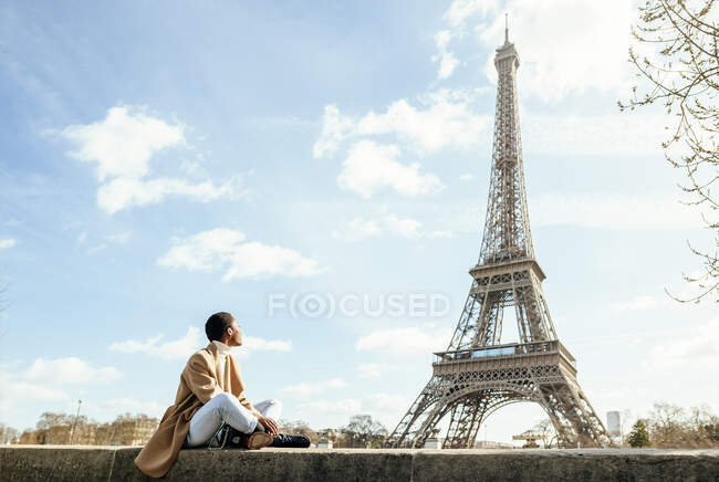 Giovane donna che guarda la Torre Eiffel contro il cielo durante la giornata di sole a Parigi, Francia — Foto stock