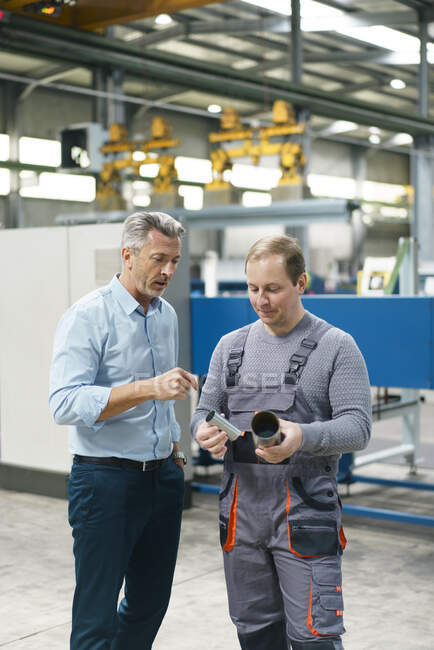 Empresario y trabajador examinando tubería de acero en una fábrica - foto de stock