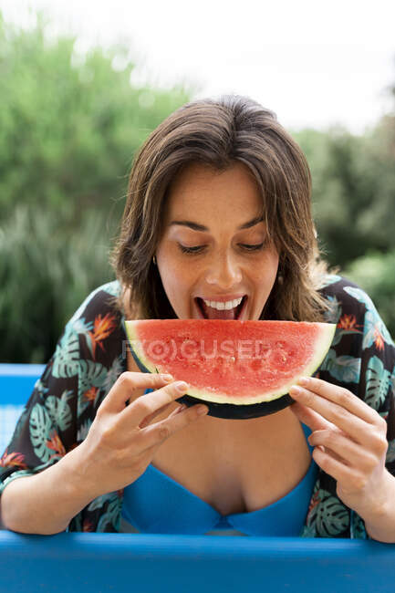 Glückliche junge Frau isst Wassermelone in aufblasbarem Schwimmbad auf Hof — Stockfoto