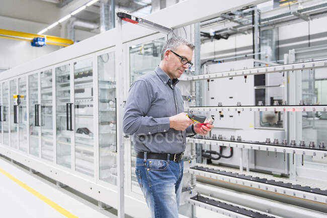 Hombre usando escáner de código de barras en un producto en una fábrica - foto de stock