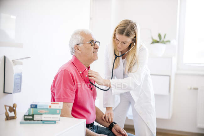 Female doctor examining senior patient in medical clinic — Stock Photo