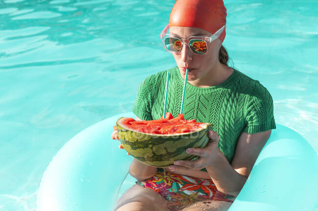 Retrato de mulher com pneu flutuante e melancia na piscina — Fotografia de Stock