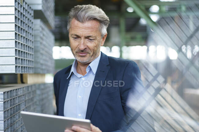 Mature businessman using tablet in a factory — Stock Photo