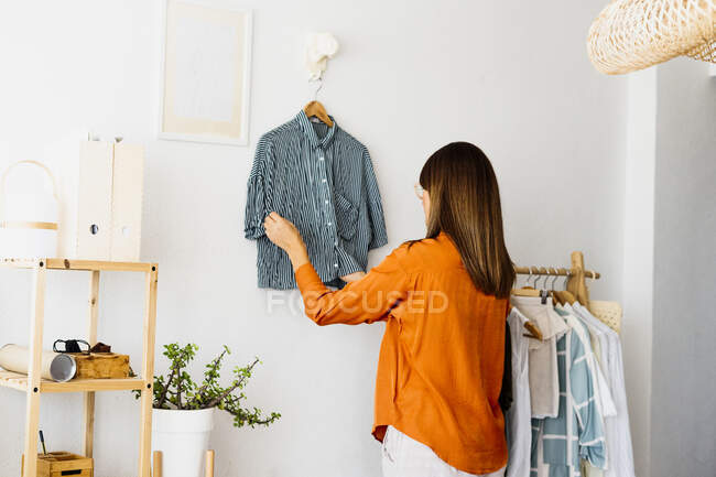 Женщина-модельер, работающая дома, вешает одежду — стоковое фото