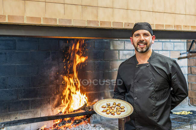 Traditional cooking in restaurant ktichen, chef showing plate with grilled seafood — Stock Photo