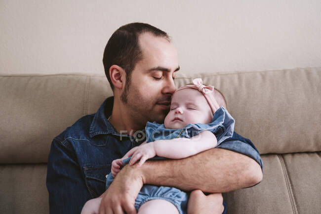 Papà che porta la bambina addormentata sul divano a casa — Foto stock