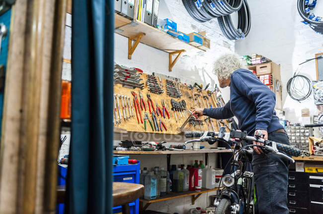 Mecánico de bicicletas trabajando en tienda de bicicletas - foto de stock