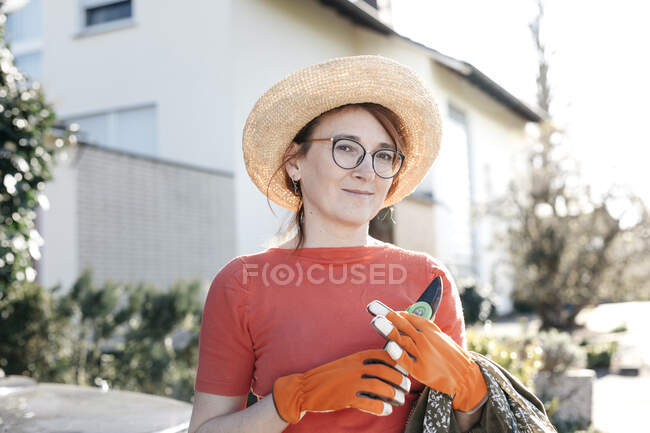 Portrait of mature woman with pruner wearing straw hat and gardening gloves — Stock Photo