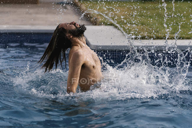 Uomo barbuto in piscina spruzzi d'acqua — Foto stock