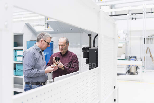 Due uomini d'affari che esaminano il prodotto in una fabbrica — Foto stock