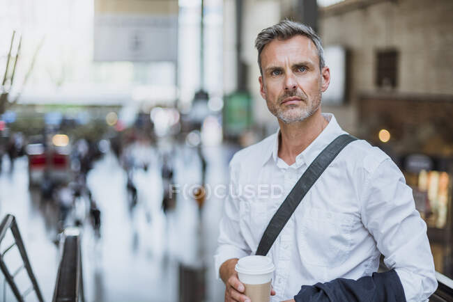 Fiducioso uomo d'affari serio in possesso di caffè mentre in piedi in città — Foto stock