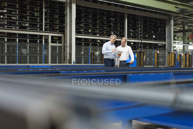 Due uomini d'affari con tablet che parlano in una fabbrica — Foto stock