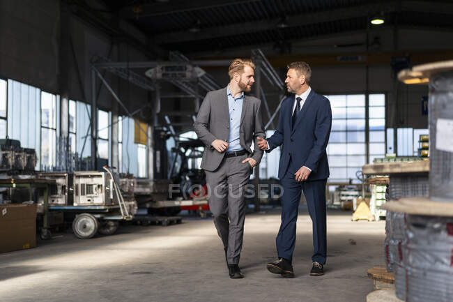 Два бизнесмена ходят и разговаривают на фабрике — стоковое фото