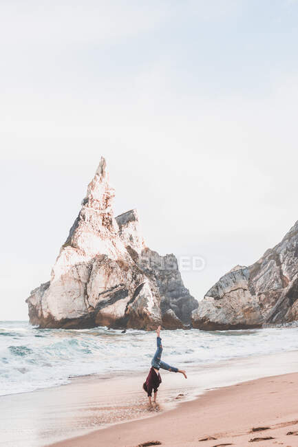 Mujer tocando handstand en la playa de Ursa, Región de Lisboa, Portugal - foto de stock