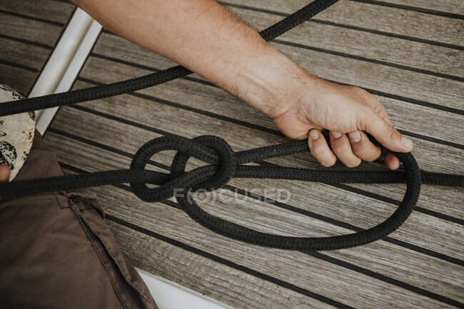 Руки моряка, завязывающего морской узел в парусник — стоковое фото