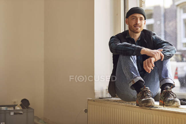 Hombre remodelación tienda ubicación, sentado en el alféizar de la ventana - foto de stock