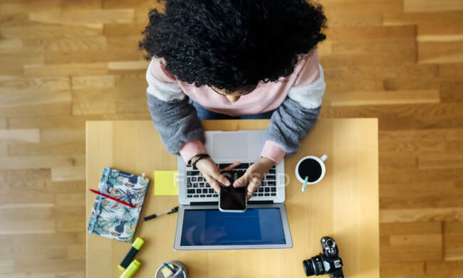 Top view of young woman working from home using smartphone — Stock Photo
