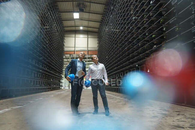 Two businessmen in a high rack warehouse of a factory — Stock Photo