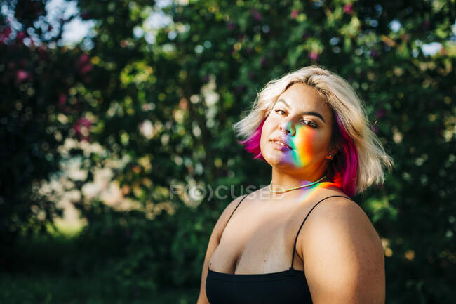 Plus size donna con luci arcobaleno che cadono sul suo viso nel parco — Foto stock