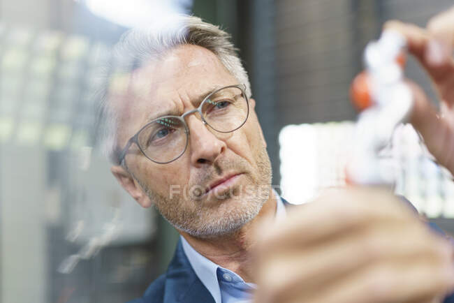 Portrait d'un homme d'affaires mature examinant un produit industriel — Photo de stock