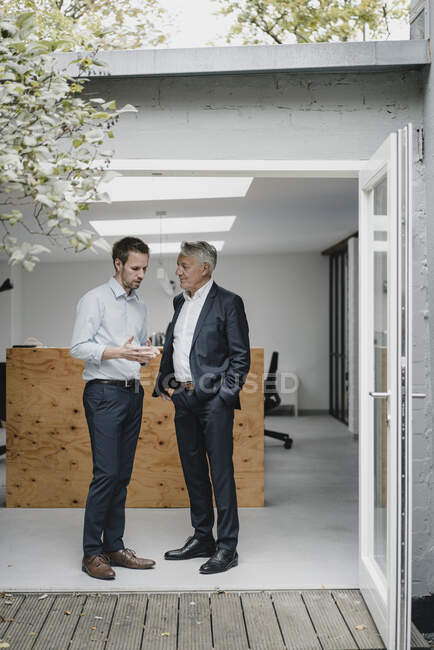Two businessmaen standing in open office door, talking — Stock Photo