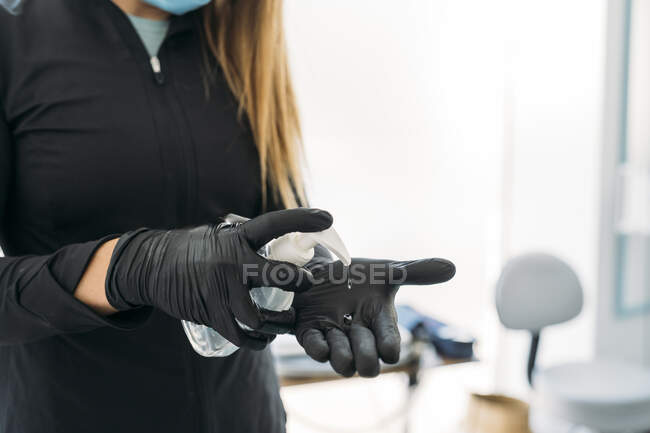 Frau trägt Schutzhandschuhe mit Händedesinfektionsmittel — Stockfoto