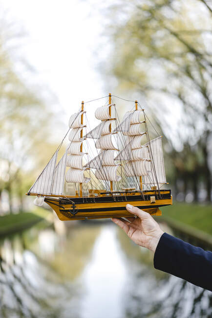 Hand of a man holding model ship at a channel — Stock Photo